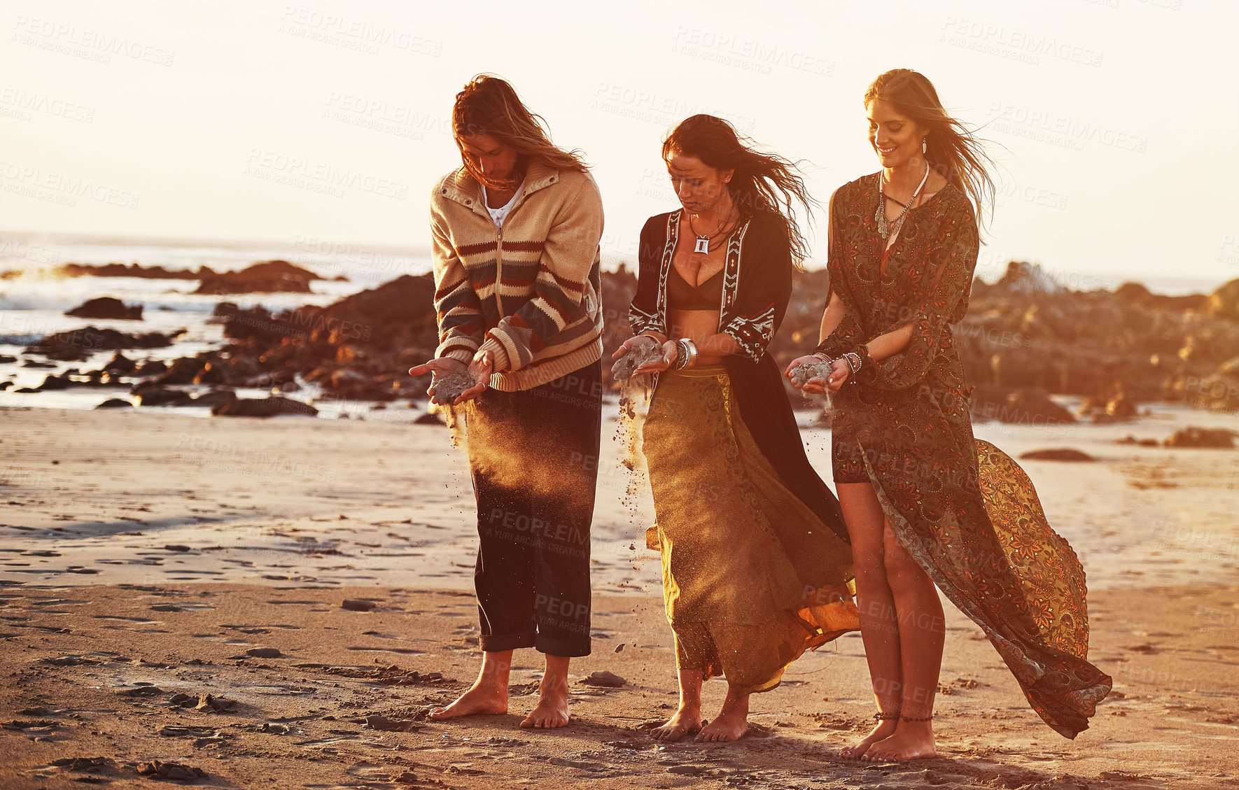 Buy stock photo Shot of three gypsies holding sand in their hands on the beach