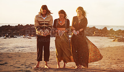 Buy stock photo Shot of three gypsies holding sand in their hands on the beach