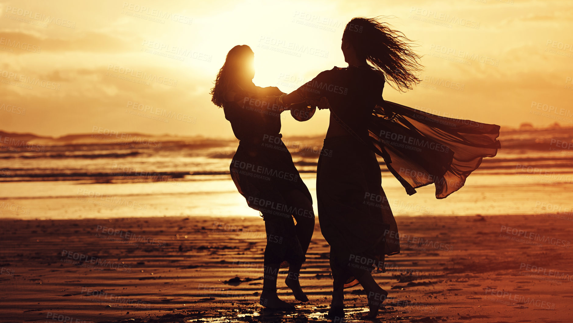 Buy stock photo Shot of two young women spending the day at the beach at sunset