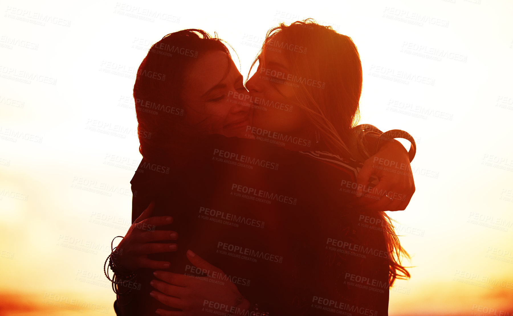 Buy stock photo Shot of two young women spending the day at the beach at sunset