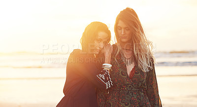 Buy stock photo Shot of two young women spending the day at the beach at sunset