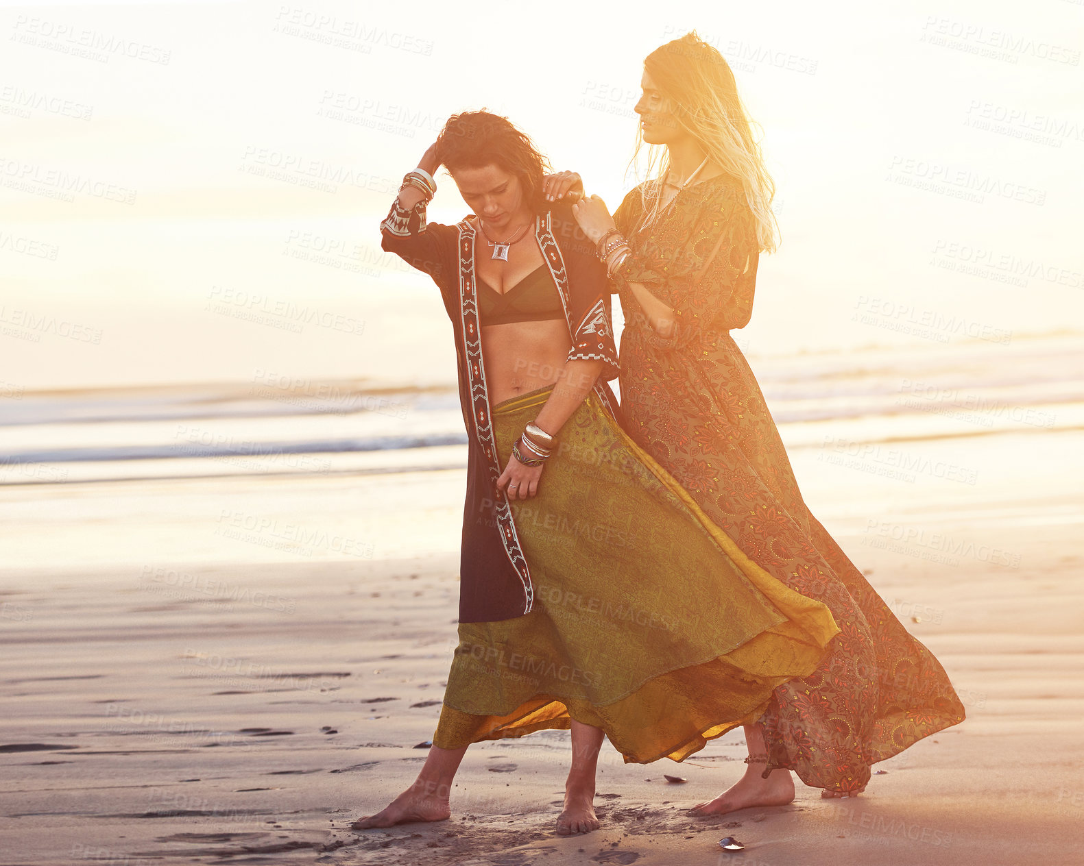 Buy stock photo Shot of two young women spending the day at the beach at sunset