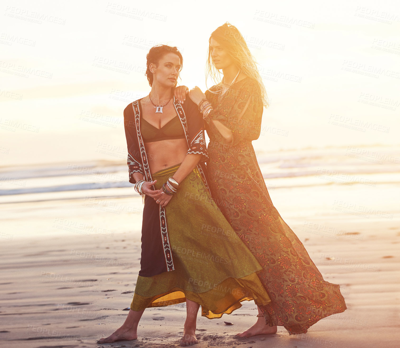 Buy stock photo Shot of two young women spending the day at the beach at sunset