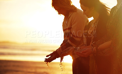 Buy stock photo Shot of three gypsies holding sand in their hands on the beach