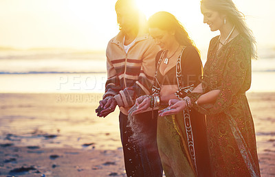 Buy stock photo Shot of three gypsies holding sand in their hands on the beach