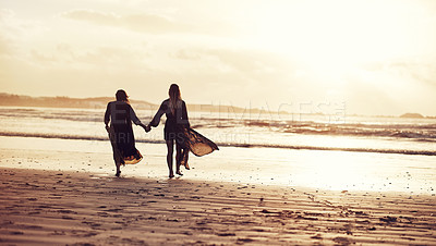 Buy stock photo Shot of two young women spending the day at the beach at sunset