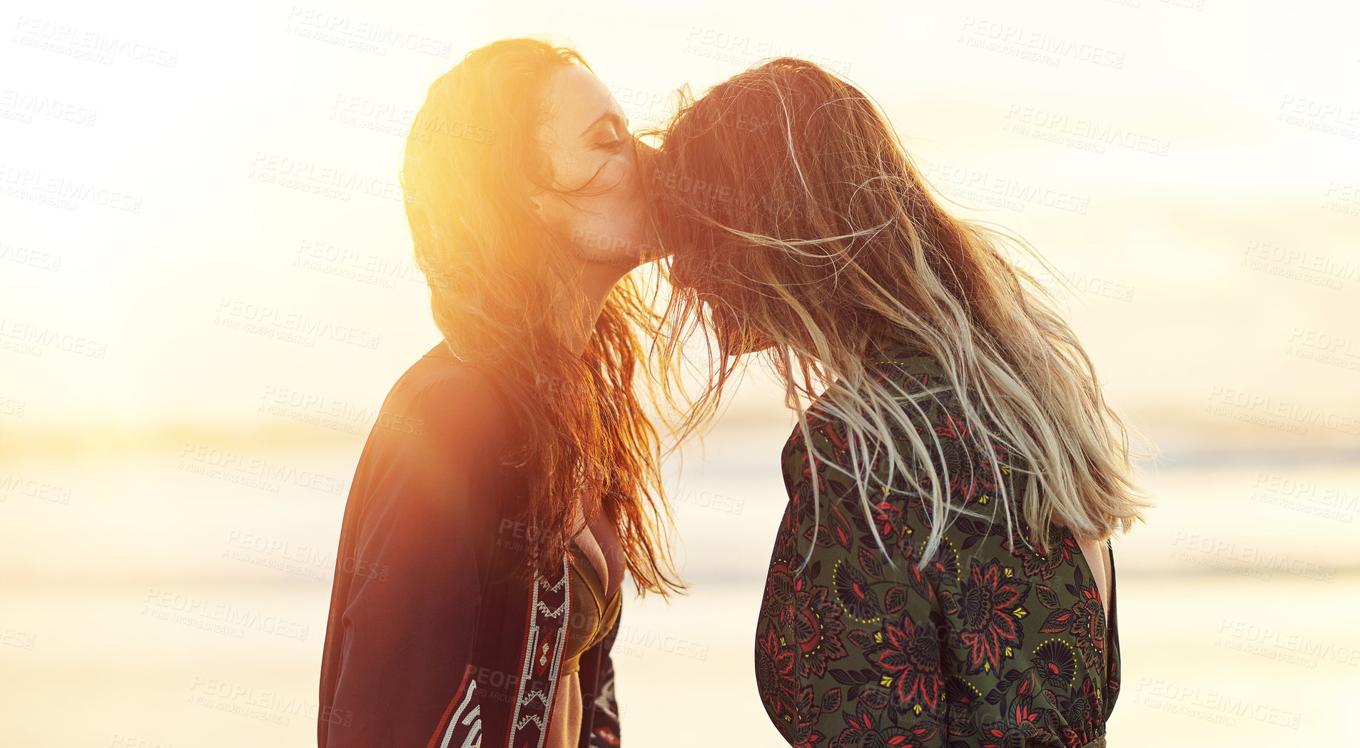 Buy stock photo Shot of two young women spending the day at the beach at sunset