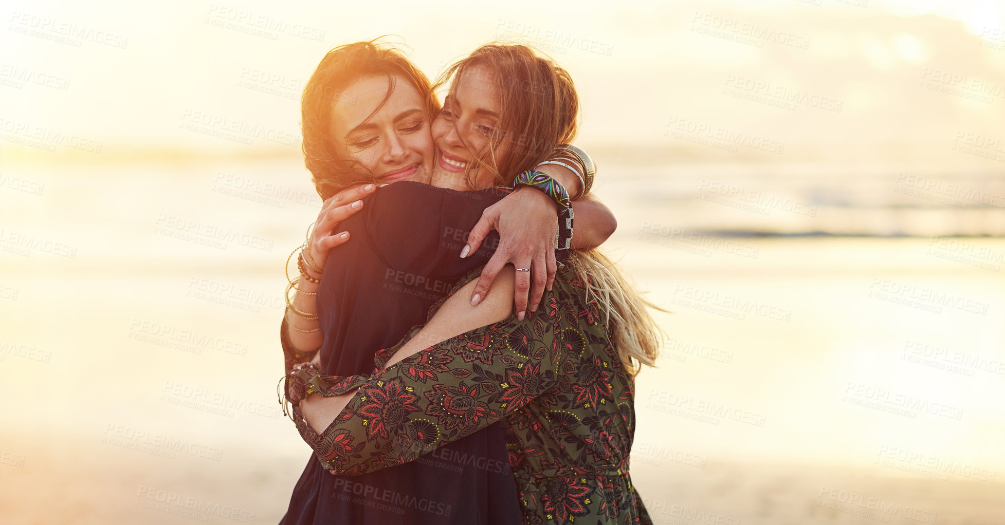 Buy stock photo Shot of two young women spending the day at the beach at sunset