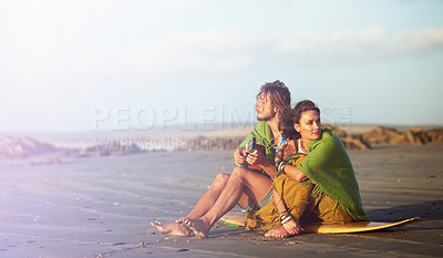 Buy stock photo Shot of a young man playing the guitar while sitting on the beach with his girlfriend