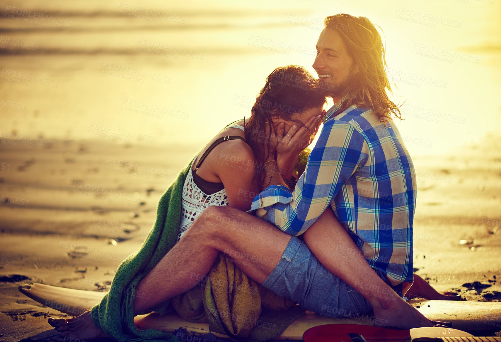 Buy stock photo Shot of a couple sitting on the beach with their legs intertwined