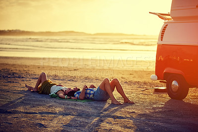 Buy stock photo Shot of an affectionate young couple lying on the beach