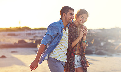 Buy stock photo Shot of a happy young couple going for a walk along the beach
