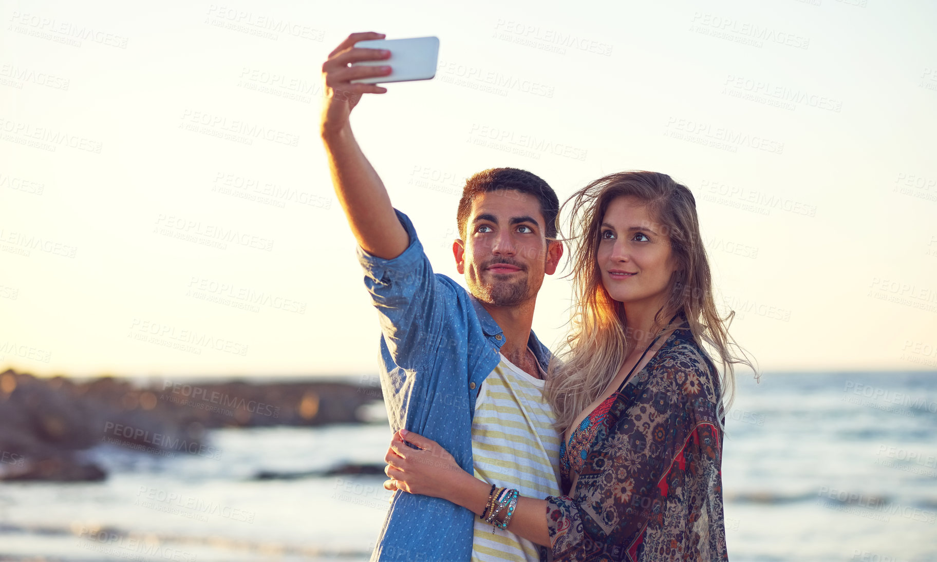 Buy stock photo Shot of an happy young couple taking selfies at the beach