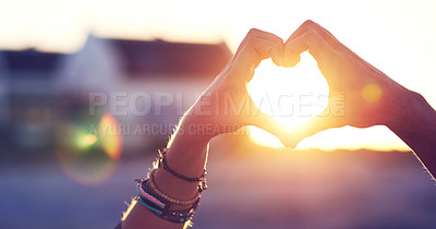 Buy stock photo Cropped shot of a couple making a heart shape with their hands against a sunset background