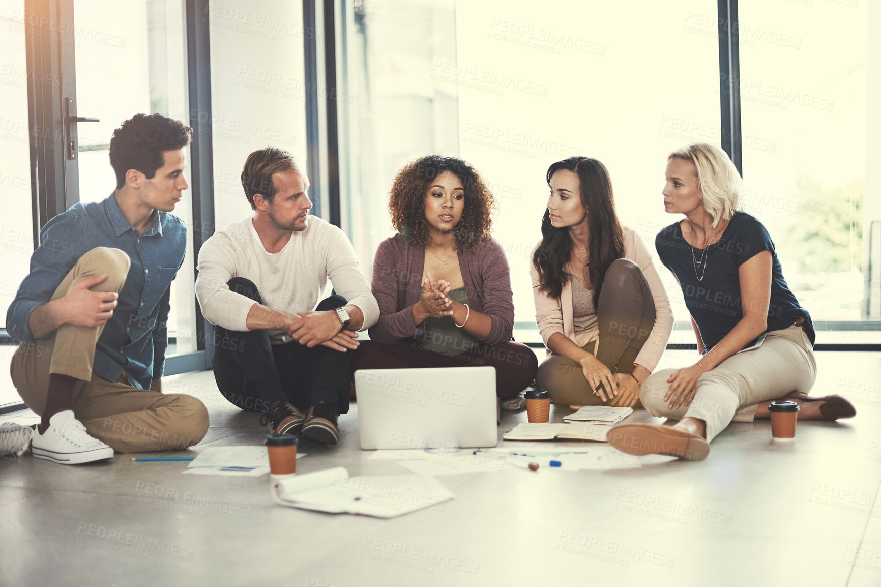 Buy stock photo Shot of a team of designers brainstorming on the floor in an office