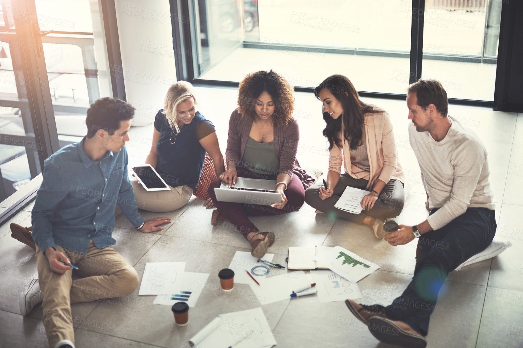 Buy stock photo Shot of a team of designers brainstorming on the floor in an office