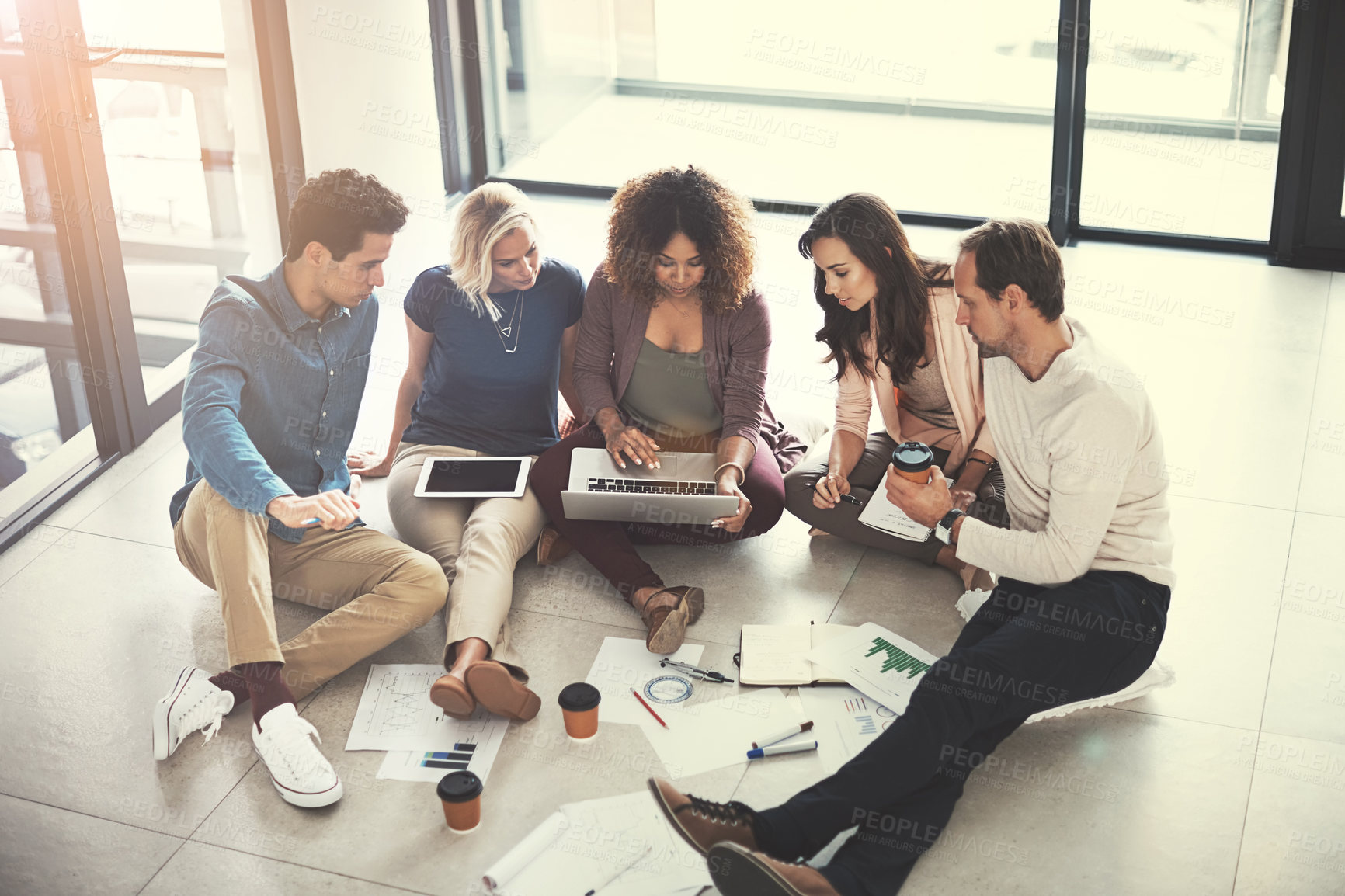 Buy stock photo Shot of a team of designers brainstorming on the floor in an office