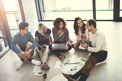 Buy stock photo Shot of a team of designers brainstorming on the floor in an office