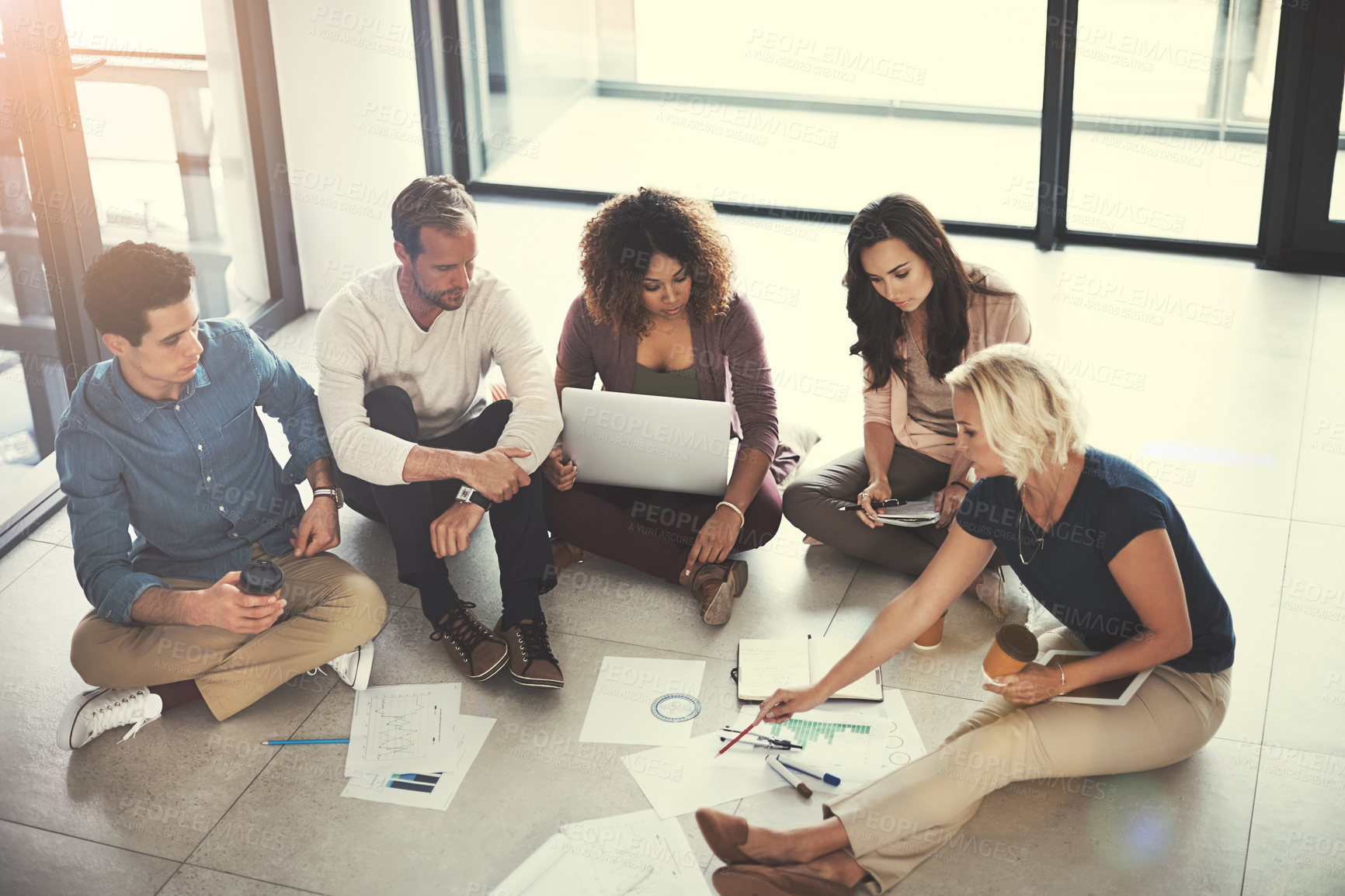 Buy stock photo Shot of a team of designers brainstorming on the floor in an office