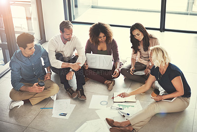 Buy stock photo Shot of a team of designers brainstorming on the floor in an office