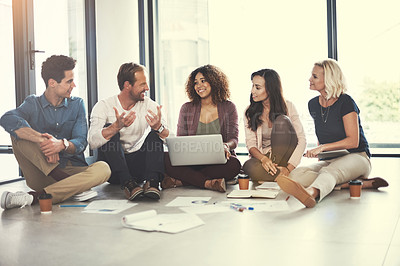 Buy stock photo Shot of a team of designers brainstorming on the floor in an office