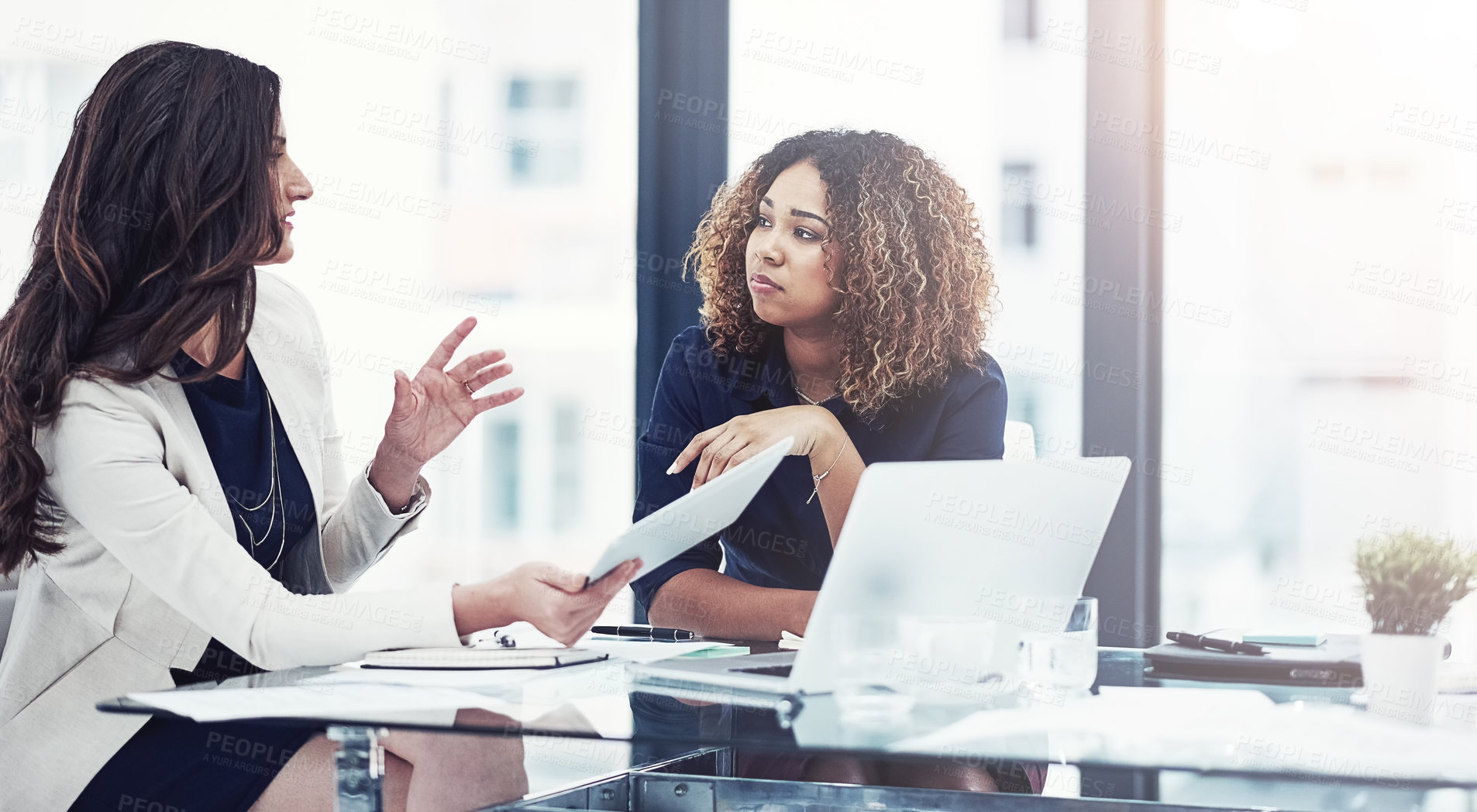 Buy stock photo Shot of two businesswomen using a digital tablet together during a collaboration at work