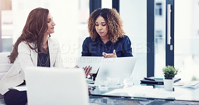Buy stock photo Shot of two businesswomen using a digital tablet together during a collaboration at work