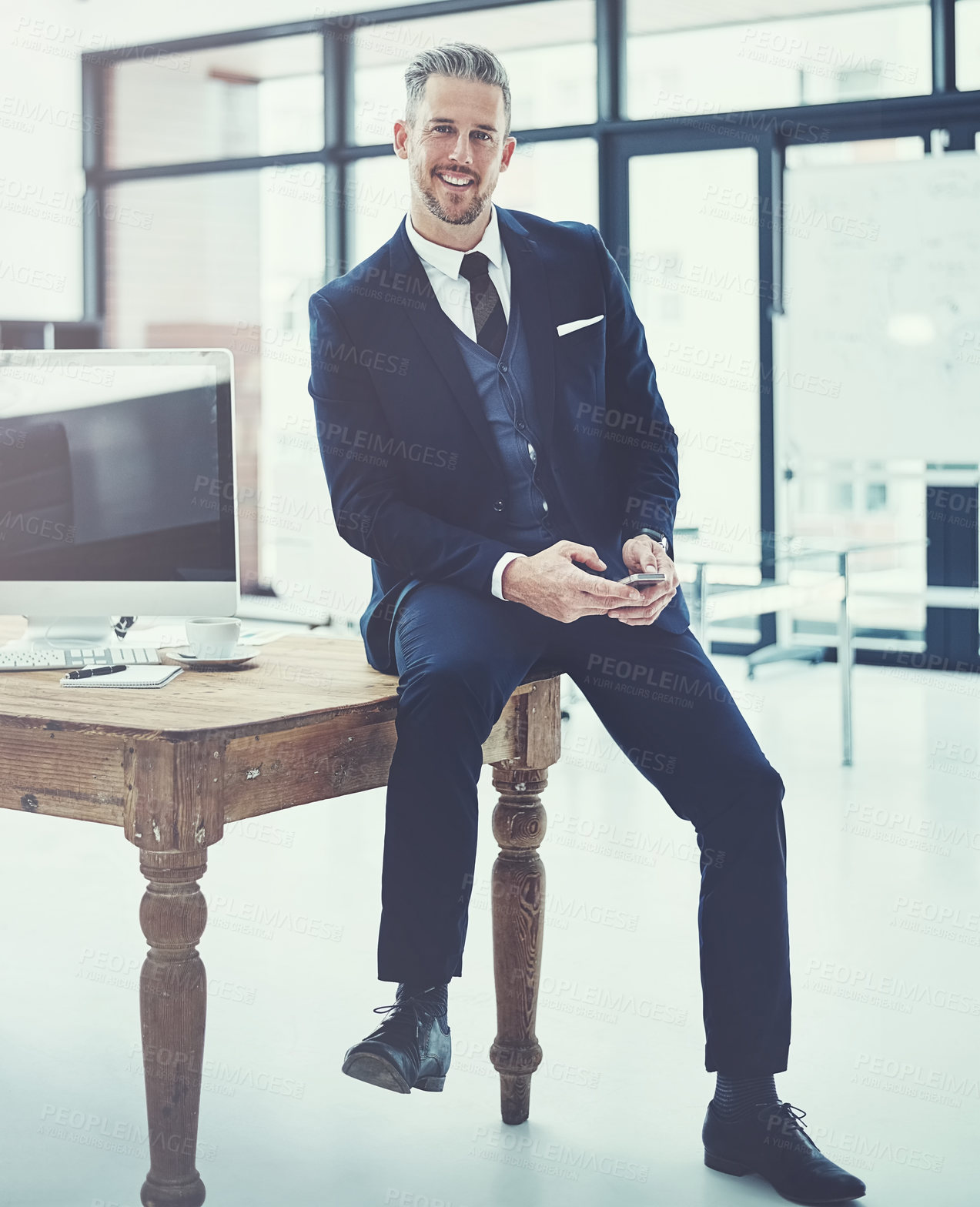 Buy stock photo Shot of a mature businessman using a cellphone at his desk in a modern office