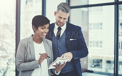 Buy stock photo Shot of a businesswoman and businessman using a notepad together at work
