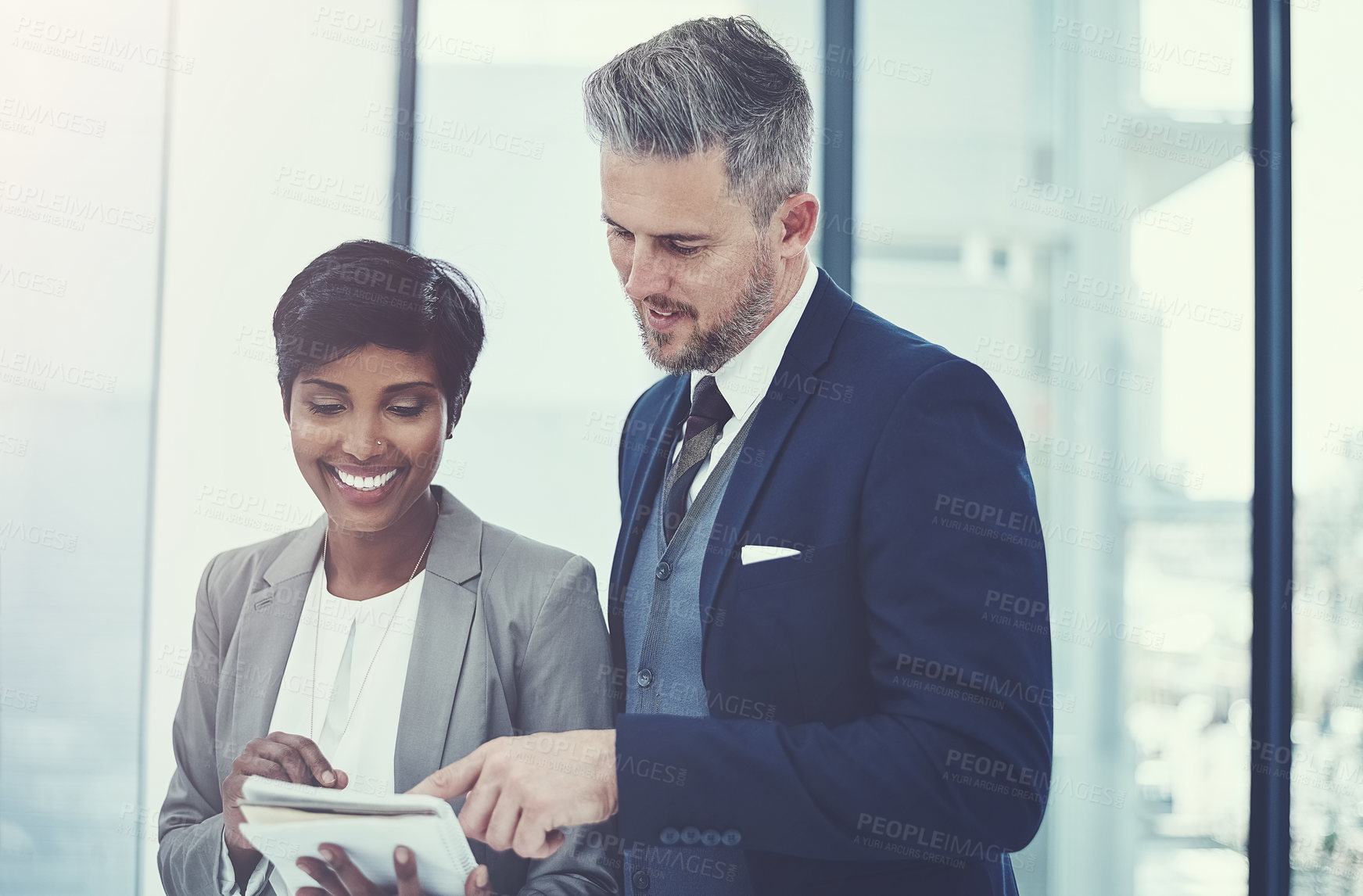 Buy stock photo Shot of a businesswoman and businessman using a notepad together at work