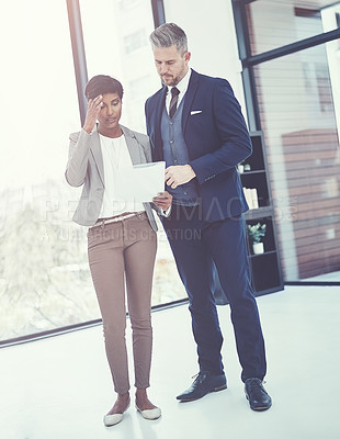 Buy stock photo Shot of a businesswoman and businessman reading a document together at work