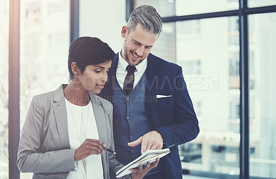 Buy stock photo Shot of a businesswoman and businessman using a notepad together at work