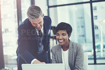 Buy stock photo Shot of a businesswoman and businessman using a laptop together at work