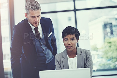Buy stock photo Shot of a businesswoman and businessman using a laptop together at work