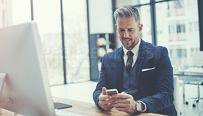 Buy stock photo Shot of a mature businessman using a cellphone at his desk in a modern office