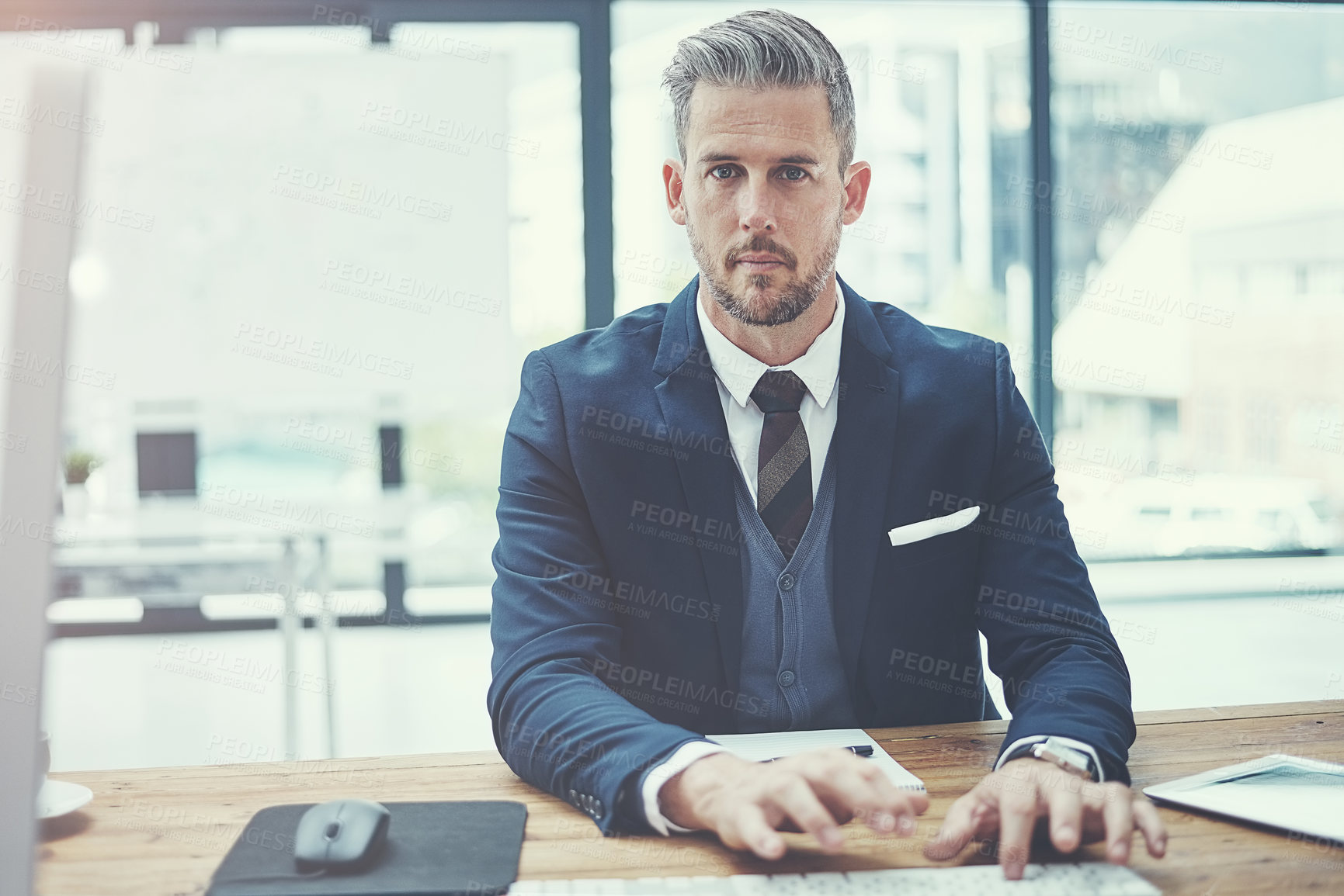 Buy stock photo Portrait of a mature businessman using a computer at his desk in a modern office