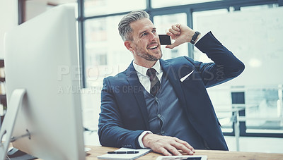 Buy stock photo Shot of a mature businessman using a cellphone at his desk in a modern office