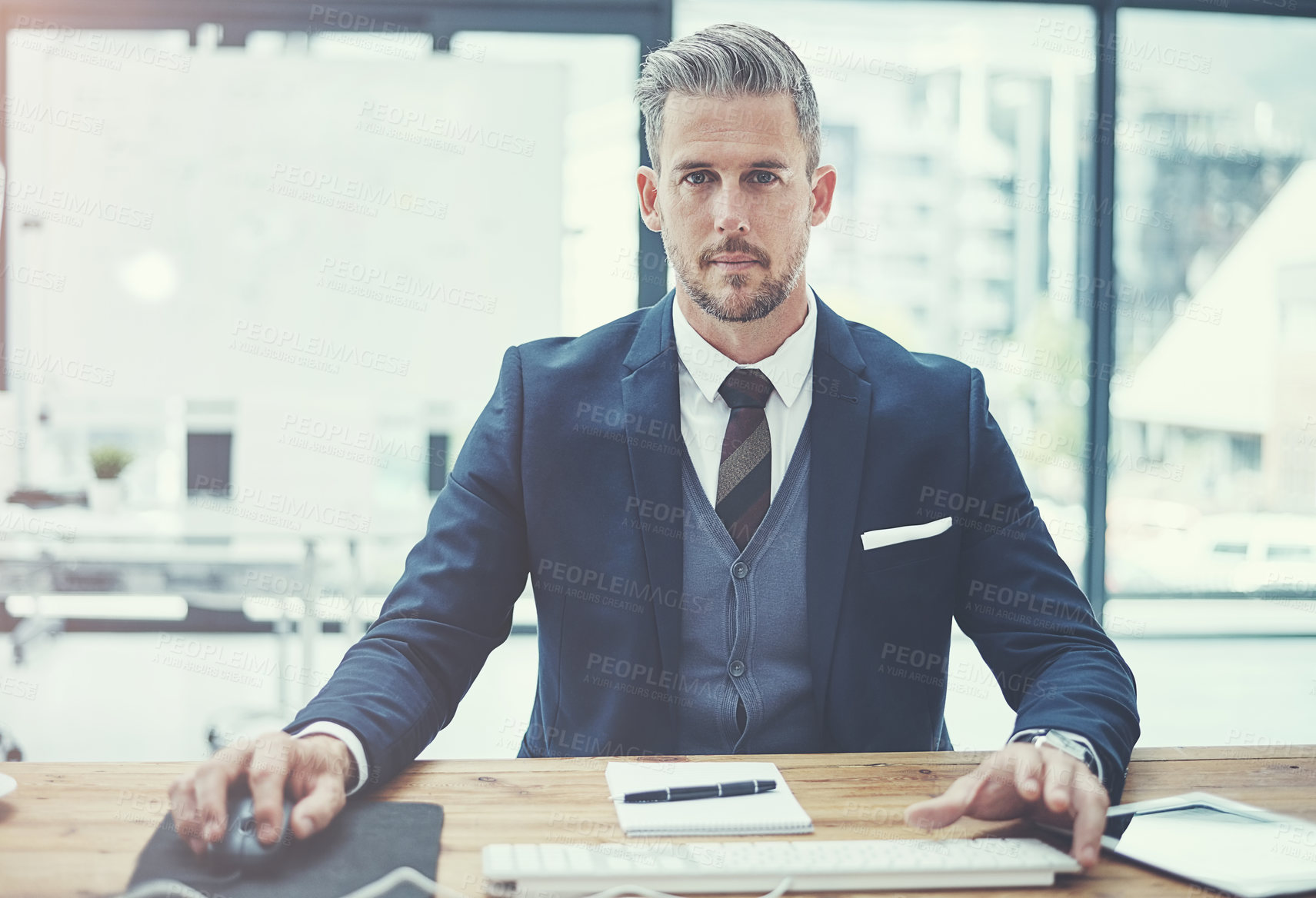 Buy stock photo Portrait of a mature businessman using a computer at his desk in a modern office