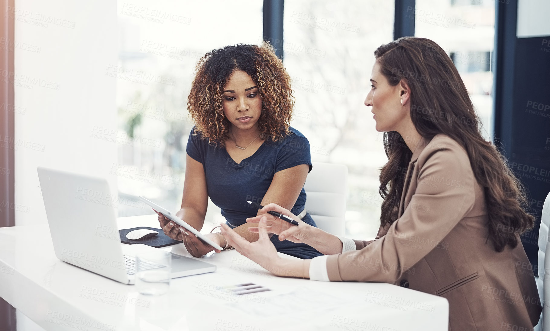 Buy stock photo Shot of two businesswomen using a digital tablet together during a collaboration at work