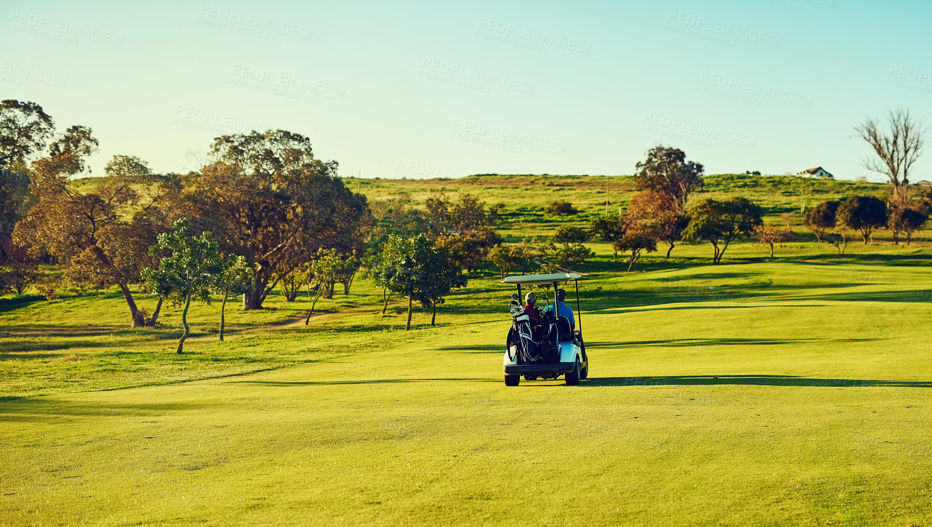 Buy stock photo Shot of two golfers riding in a cart on a golf course