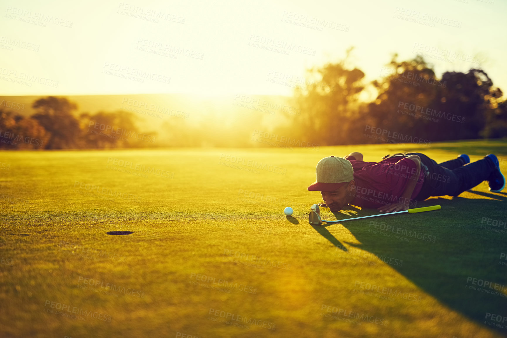 Buy stock photo Shot of a young man eyeing up the putt during a round of golf