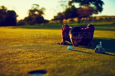 Buy stock photo Shot of a young man eyeing up the putt during a round of golf