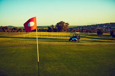 Buy stock photo Shot of two golfers riding in a cart on a golf course