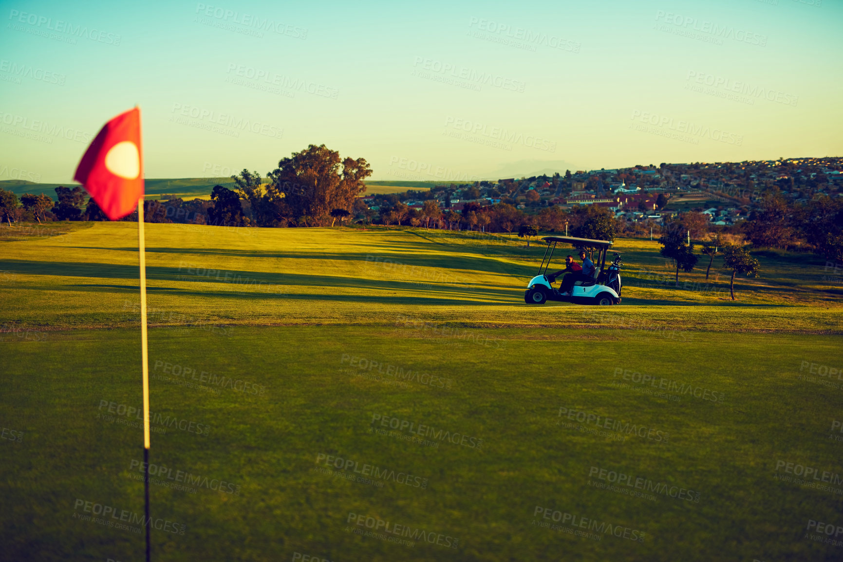 Buy stock photo Shot of two golfers riding in a cart on a golf course