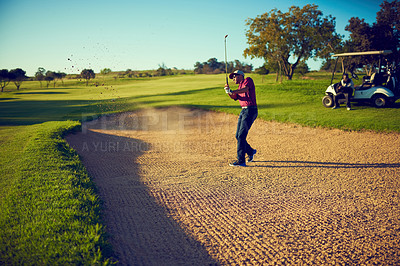 Buy stock photo Shot of a golfer chipping his ball out of a bunker