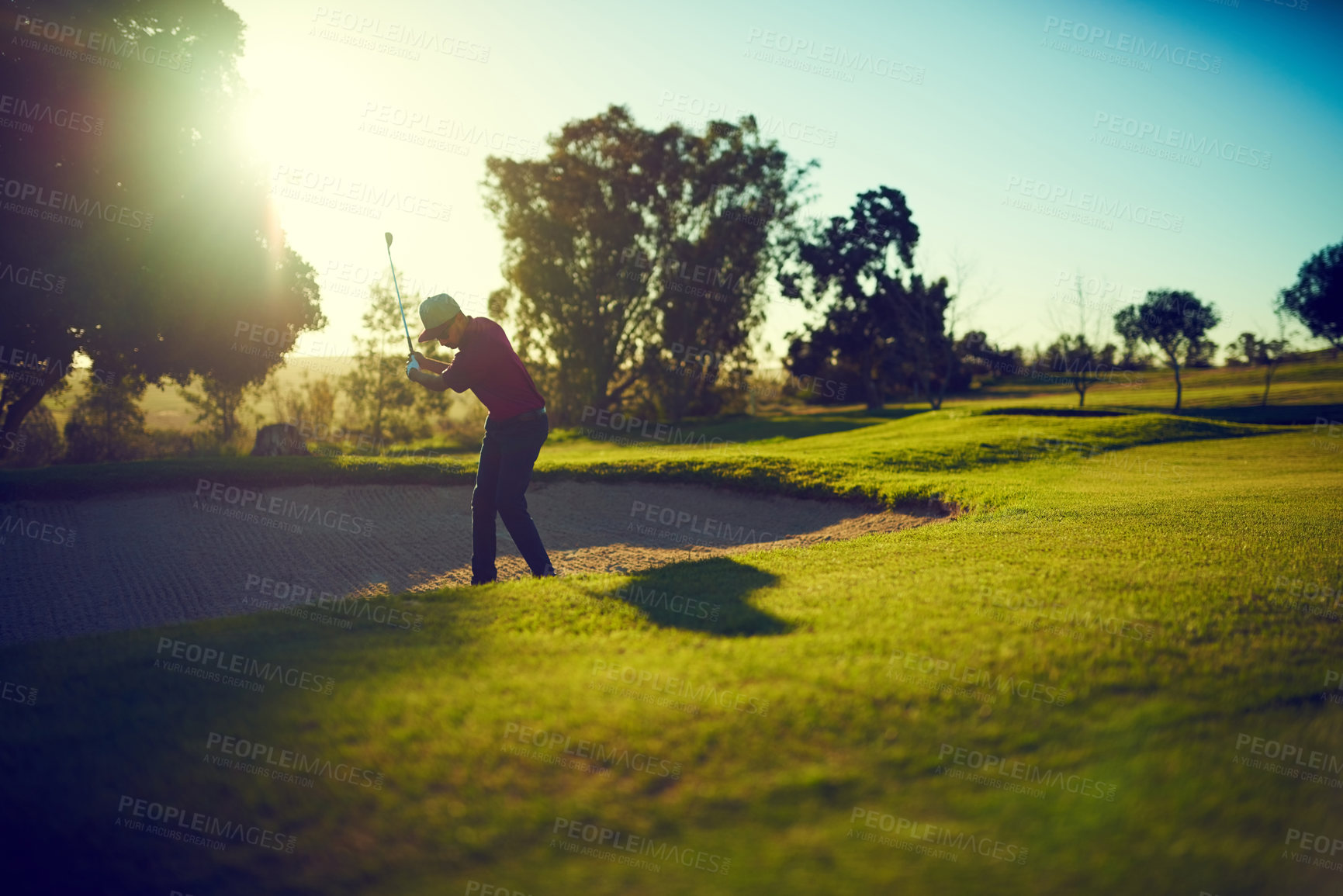 Buy stock photo Shot of a young man hitting the ball out of the bunker during a round of golf