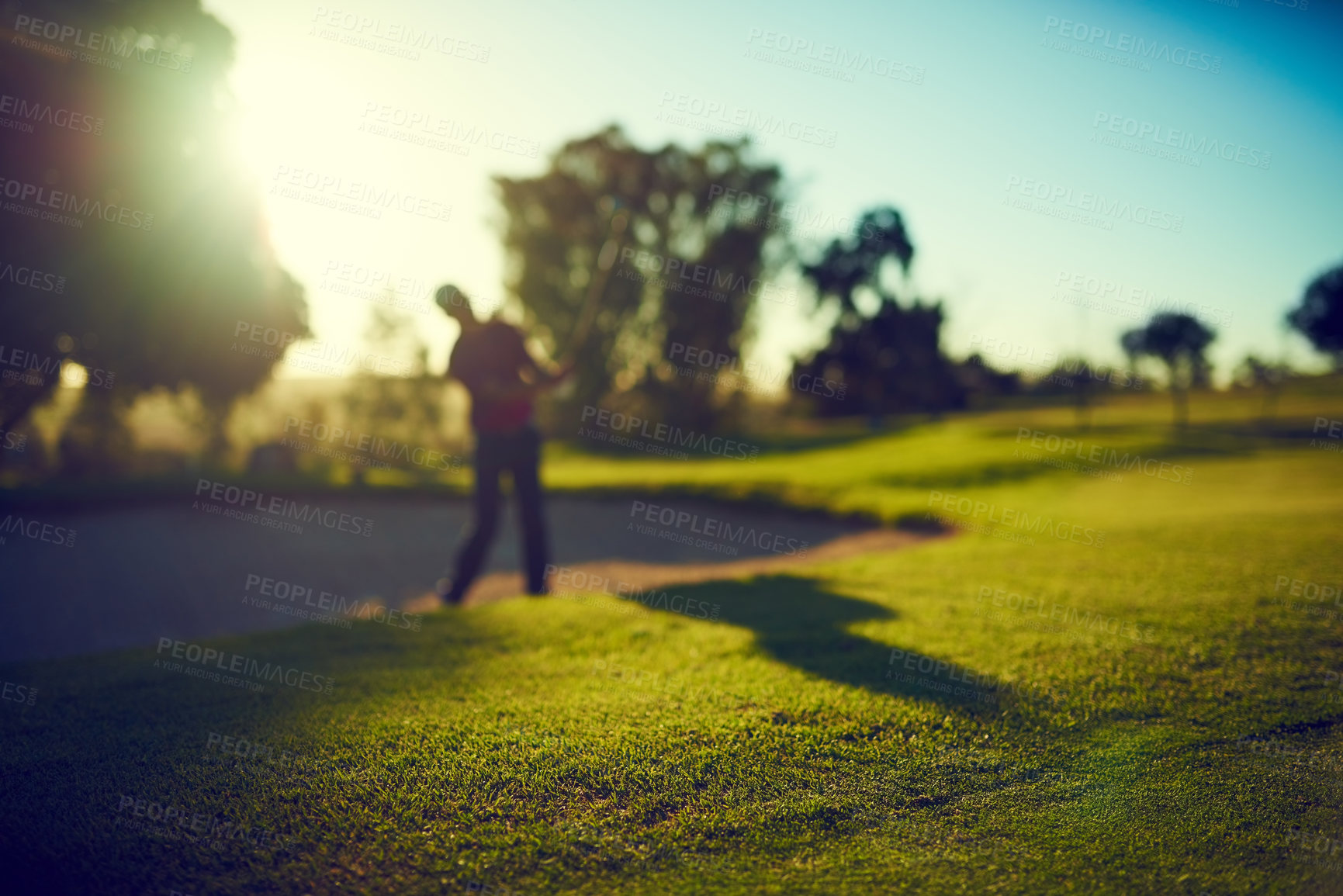 Buy stock photo Shot of a young man hitting the ball out of the bunker during a round of golf