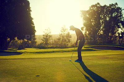 Buy stock photo Shot of a young man hitting the ball out of the bunker during a round of golf