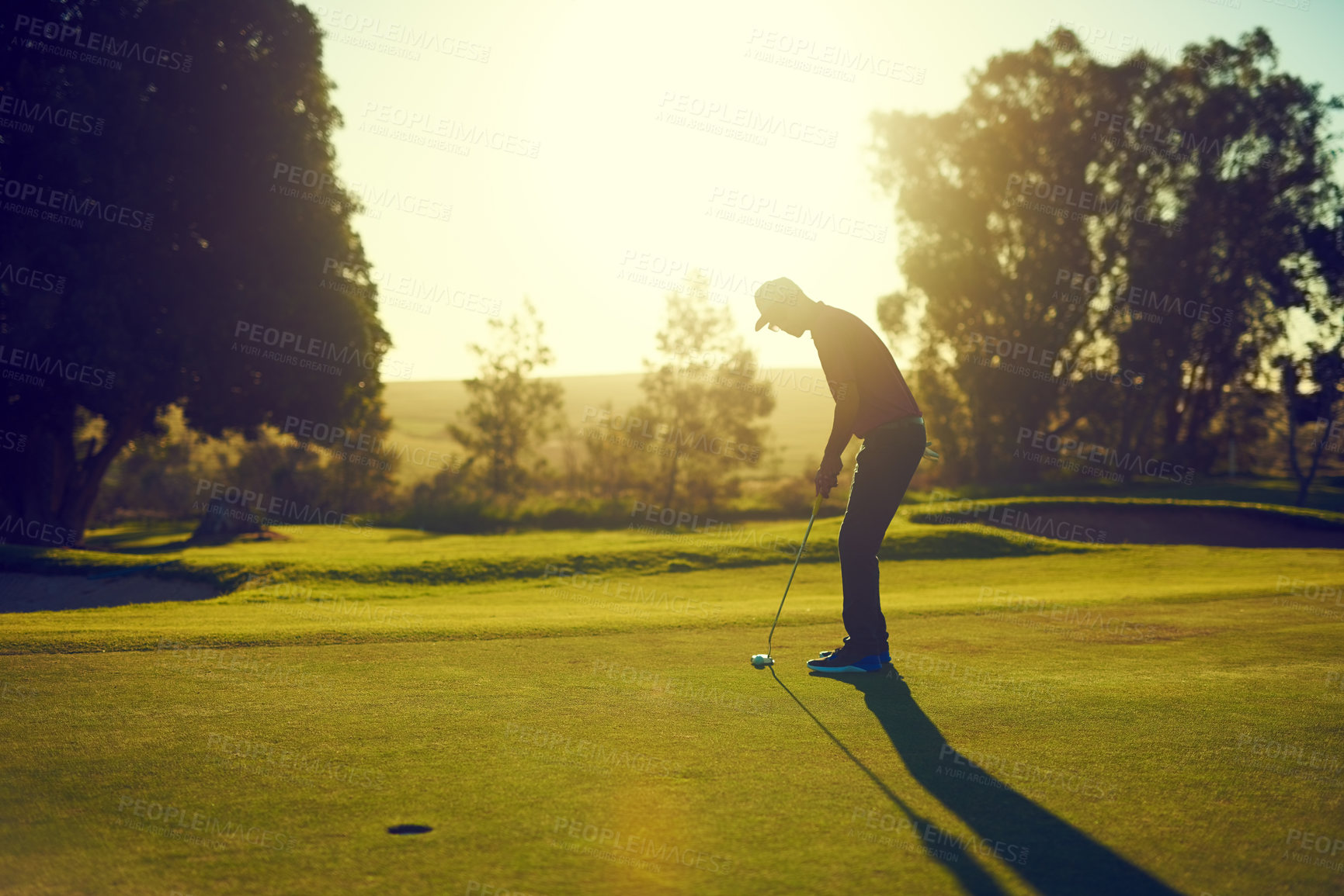 Buy stock photo Shot of a young man hitting the ball out of the bunker during a round of golf