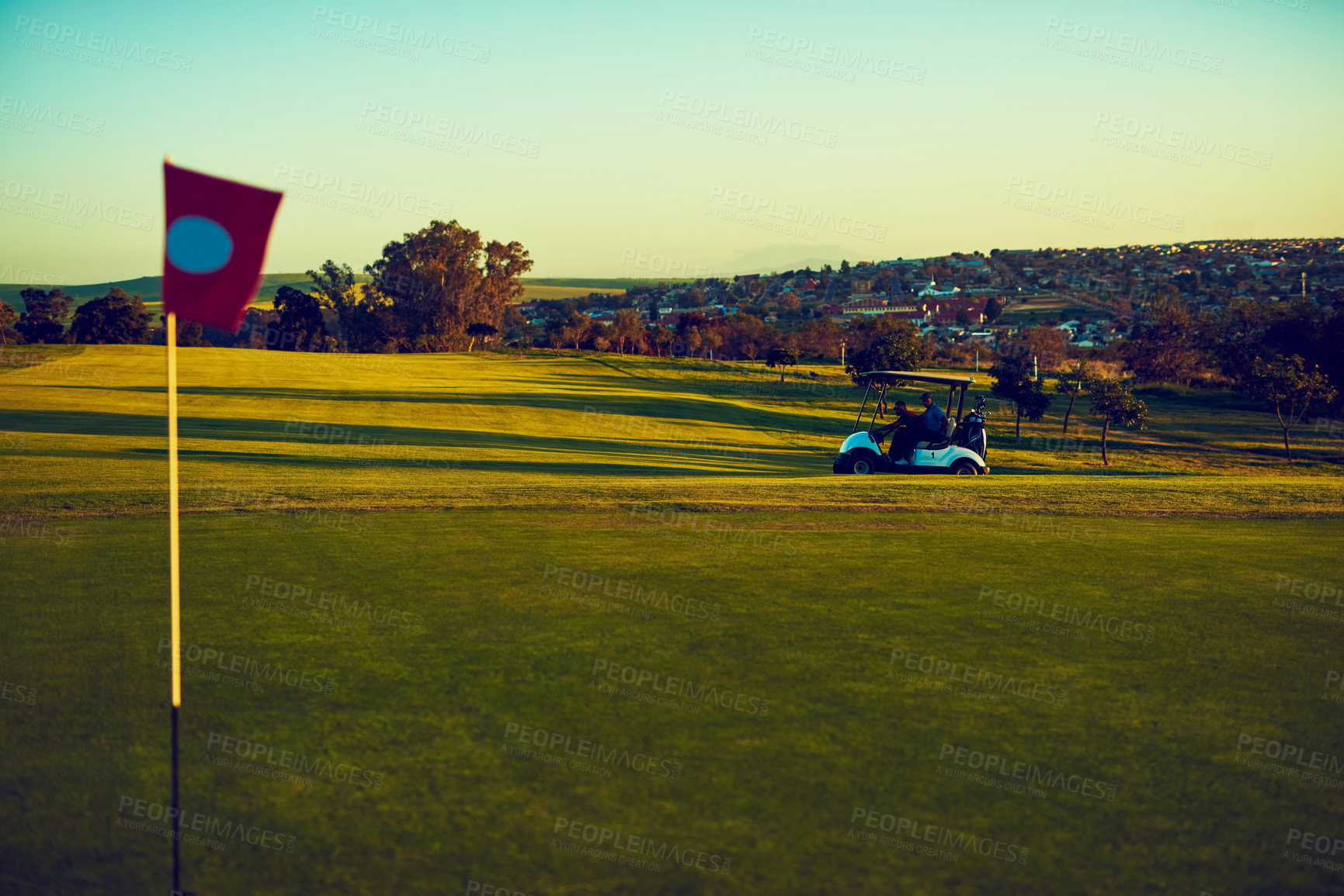 Buy stock photo Shot of two golfers riding in a cart on a golf course